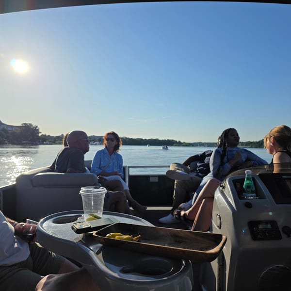 Several people on a boat enjoying a sunny day on the water with snacks.