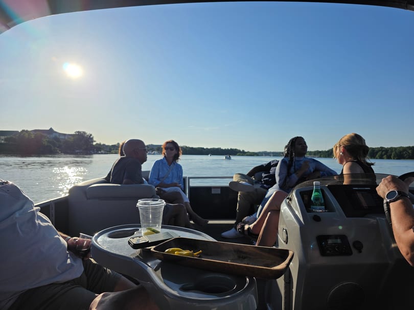 Several people on a boat enjoying a sunny day on the water with snacks.