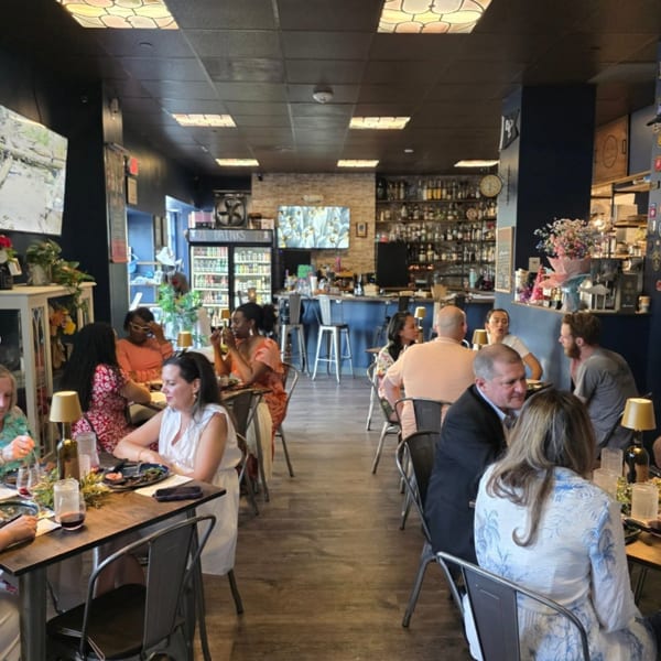 Diners enjoying meals and drinks in a lively restaurant with a full bar in the background.