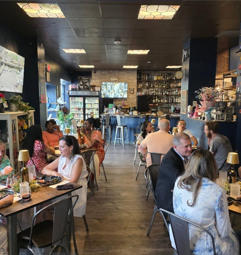 Diners enjoying meals and drinks in a lively restaurant with a full bar in the background.